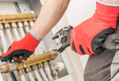 Gloved hands tightening a brass plumbing manifold with a wrench
